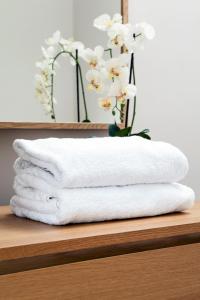 a stack of towels on a shelf with a vase with white flowers at Madison Hill - Bedford Hill 1 - One bedroom flat in London