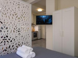 Schlafzimmer mit weißen Wänden, einem TV und Handtüchern in der Unterkunft Casa Del Centro Storico,By IdealStay Experience in Iraklio