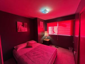 Dormitorio rojo con cama y ventana en Cozy Artistic Room Available in Delta Surrey Best Price en Delta
