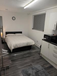 a white bedroom with a bed and a microwave at 188 marsh road in Luton