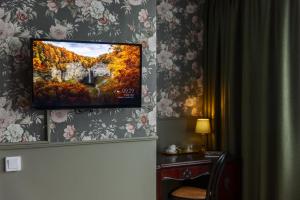 a flat screen tv hanging on a wall with floral wallpaper at Gibsons Hotell in Jonsered