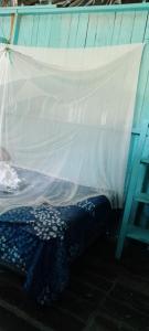 a bed with a white sheet on top of it at Hospedaje y jardin botanico chiltun maya in El Remate