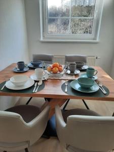 a wooden table with plates and bowls of fruit on it at Wohnen in Graz Mariatrost in Graz