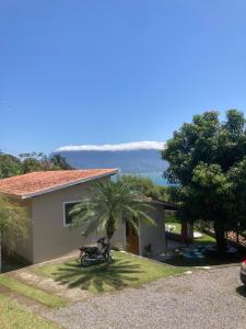 a house with a palm tree and a motorcycle in the yard at Casas No Centro Histórico (vila) in Ilhabela