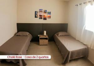 two beds in a small room with a window at Chalés Vila da Rosa in Ribeirão Claro