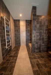 a walk in shower with brown tiled walls at Appartement 1 in Diever