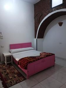 1 dormitorio con 1 cama rosa en una habitación en Egypt lovers home, en Luxor