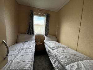 2 camas en una habitación pequeña con ventana en Lovely 8 Berth Caravan At Highfield Grange In Essex Ref 26213o, en Clacton-on-Sea