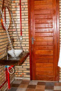 uma casa de banho com uma porta de madeira e um lavatório em pousada Baloiço em Caucaia