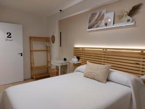 1 dormitorio con cama blanca y cabecero de madera en Pensión Cabezas Oviedo en Oviedo