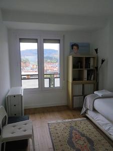 a bedroom with a bed and a large window at EGONA-ZUM8 Vista espectacular,piscina,tenis,playa in Zarautz