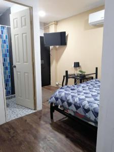 a bedroom with a bed and a tv and a door at Comfort Home Escalón in San Salvador