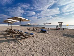 un gruppo di sedie e ombrelloni in spiaggia di Luxury the address 3BR a Fujaira