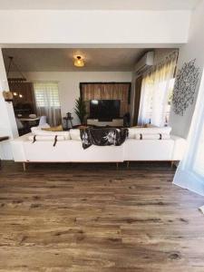 Tribeka House في Islote: غرفة معيشة مع أرائك بيضاء وتلفزيون بشاشة مسطحة