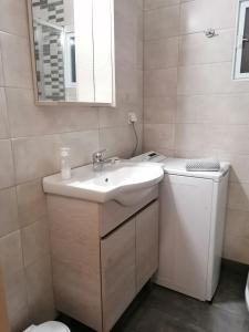 a bathroom with a sink and a washing machine at Marinos Studios - 2nd floor studio in Póros Kefalonias