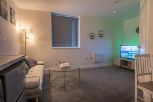 a living room with a couch and a table and a tv at 1 Bedroom Apartment - Netflix - Close To City Centre And NEC in Birmingham