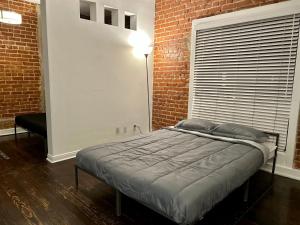 Cama en habitación con pared de ladrillo en Chic Urban Retreat - 5 Mins to LACMA Lights, en Los Ángeles