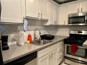 a kitchen with white cabinets and a sink and a stove at Chic Urban Retreat - 5 Mins to LACMA Lights in Los Angeles