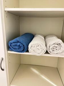 three towels on a shelf in a closet at Private rooms near metro, free parking in Helsinki