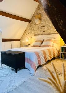 1 dormitorio con 1 cama grande y pared de piedra en Le Cottage des Chalands, en Saint-Georges-sur-Cher