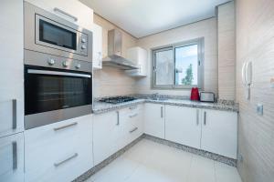 a kitchen with white cabinets and a microwave at Vue Imprenable golf-Piscine in Marrakesh