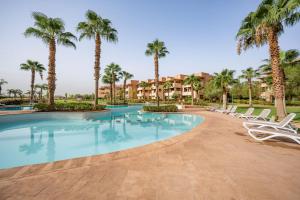 a swimming pool with lounge chairs and palm trees at Vue Imprenable golf-Piscine in Marrakesh