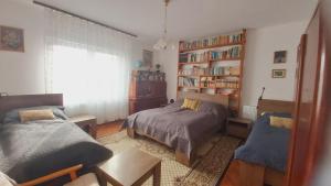 a bedroom with two beds and a book shelf at Nagyiék háza / Granny's House in Esztergom