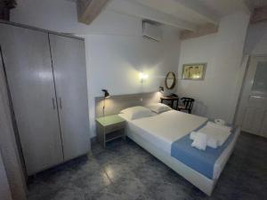 a bedroom with a large white bed and a cabinet at Diaporos Hotel in Vourvourou