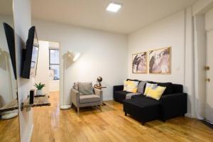 ein Wohnzimmer mit einem schwarzen Sofa und einem Stuhl in der Unterkunft 109-1 Huge 3BR Best Value Amazing NYC Apt in New York