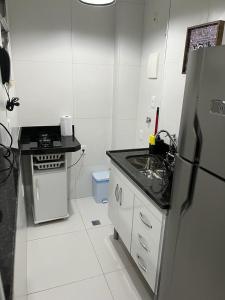 a white kitchen with a refrigerator and a sink at Copacabana AP na esquina da praia in Rio de Janeiro