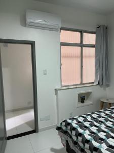 a bedroom with a bed and a window and a door at Copacabana AP na esquina da praia in Rio de Janeiro