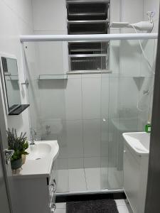 a white bathroom with a shower and a sink at Copacabana AP na esquina da praia in Rio de Janeiro