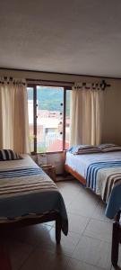 een slaapkamer met 2 bedden en een groot raam bij LA CASA DE PASCUALA in Villa Rica