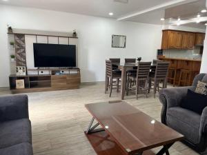 a living room with a television and a table and chairs at Crusoe (5 bedrooms, Crownpoint) in Bon Accord