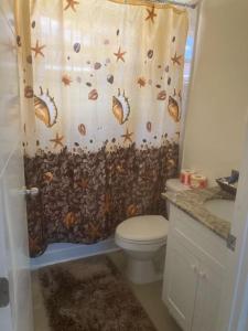 ein Badezimmer mit einem Duschvorhang mit Muscheln und einem WC in der Unterkunft MJ Manor in Old Harbour
