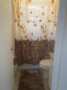 uma casa de banho com uma cortina de chuveiro com conchas e um WC em MJ Manor em Old Harbour