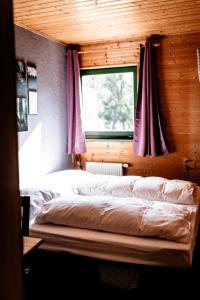 a bedroom with a bed with a window and purple curtains at heimatbude. 