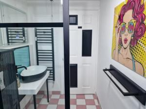 un baño con lavabo y una pintura en la pared en Flawsome stays colourful Whimsical Apartment with Garden close to Ramsgate Harbour great for families, en Ramsgate