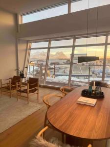 a living room with a wooden table and a large window at Leilighet med sjøutsikt og privat takterrasse. Parkering in Svolvær