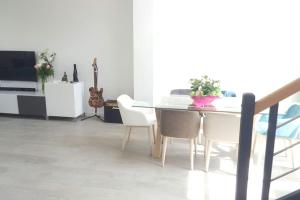 une salle à manger avec une table et des chaises blanches dans l'établissement Maison moderne proche site JO, Paris et Disneyland, à Ferrières-en-Brie
