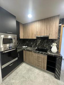 una cocina con armarios de madera y electrodomésticos negros en Apartamento La Plana II, en Castellón de la Plana