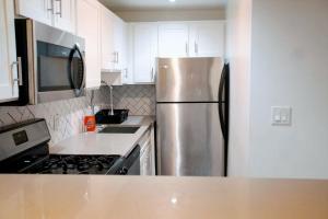 una cocina con nevera de acero inoxidable y armarios blancos en City Escape- 5 Mins to LACMA!, en Los Ángeles