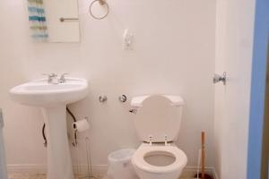 a white bathroom with a toilet and a sink at City Escape- 5 Mins to LACMA! in Los Angeles