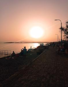 a group of people sitting on the beach at sunset at Seferihisar Akarca Denize 130 metre uzaklıkta in Seferihisar
