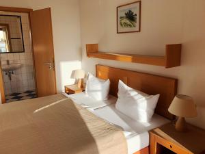 a bedroom with a bed with white pillows and a sink at Hotel Enddorn Hiddensee in Kloster