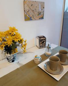 a table with two cups and a vase with yellow flowers at Lavalle Studio Buenos Aires in Buenos Aires