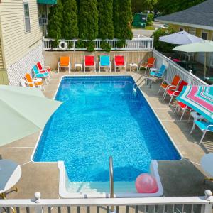 a swimming pool with chairs and umbrellas on a patio at Beach Motel and Suites in Old Orchard Beach