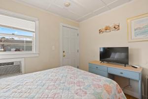 a bedroom with a bed and a flat screen tv at Beach Motel and Suites in Old Orchard Beach