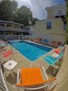 a pool with chairs and a table next to a house at Beach Motel and Suites in Old Orchard Beach