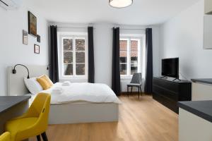 a white bedroom with a bed and a television at Primus apartments in Ljubljana